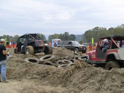 1979 Ford Bronco - Off-road vehicles navigate a challenging course, with one vehicle being pulled by another through a muddy terrain.