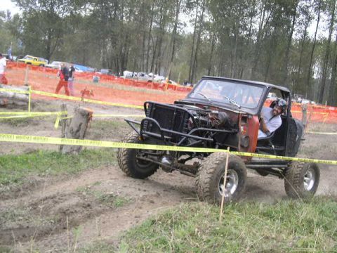 1979 Ford Bronco - Modified off-road vehicle navigates a dirt track, driver visible inside the cabin.