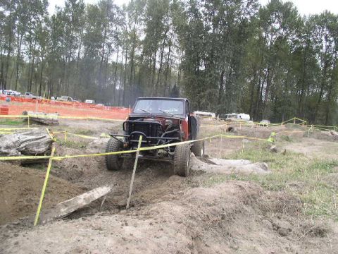 1979 Ford Bronco - A modified off-road vehicle navigates a challenging dirt course marked with yellow caution tape.
