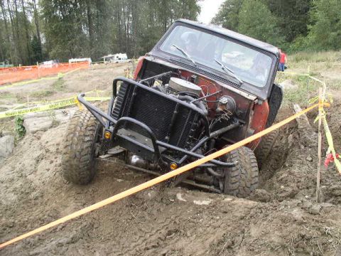 1979 Ford Bronco - This 1979 Ford Bronco is navigating a challenging off-road course, with its engine prominently displayed as it gets stuck in the mud.