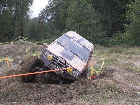1979 Ford Bronco - An off-road vehicle navigates a muddy course, displaying "WTO 4X4" on its windshield.