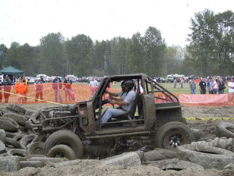 1979 Ford Bronco - A heavily modified buggy navigates a challenging mud course surrounded by tires and spectators.