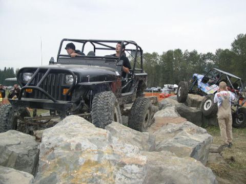 1979 Ford Bronco - Off-road vehicles tackle a challenging rock crawling course with spectators watching.