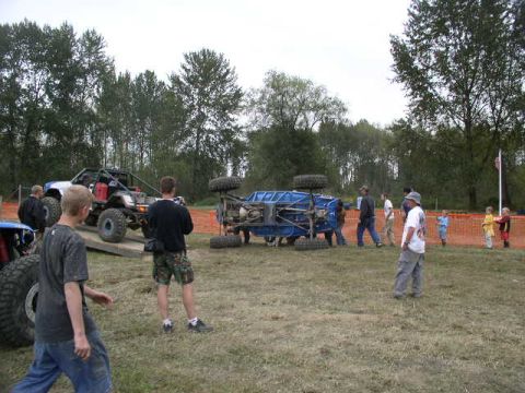 1979 Ford Bronco - An off-road event shows a blue buggy overturned on the grass, with another buggy on a ramp in the background.