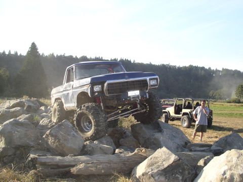 1979 Ford Bronco - A lifted 1979 Ford Bronco navigates a rocky obstacle course with other vehicles in the background.