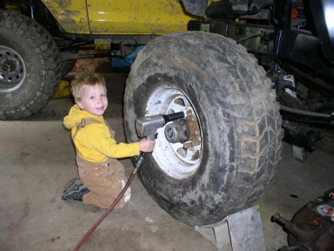 1979 Ford Bronco - Young helper gets hands-on with a large tire and impact wrench in the garage.