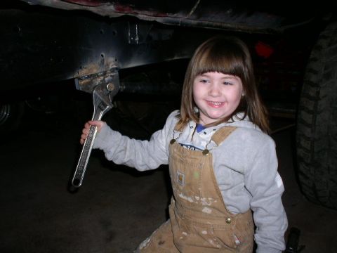 1979 Ford Bronco - A young mechanic poses with a large adjustable wrench, ready to work on the underside of a vehicle.