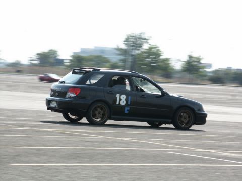 2001 Mercury Grand Marquis - A black Subaru Impreza WRX wagon is seen on a race track with another car blurred in the background.
