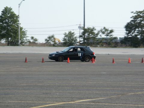 2001 Mercury Grand Marquis - A black Subaru Impreza WRX wagon navigates a course marked by orange cones on a sunny day.