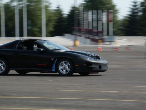 2001 Mercury Grand Marquis - A black Pontiac Firebird Trans Am is captured in motion on a race track, with motion blur indicating speed.