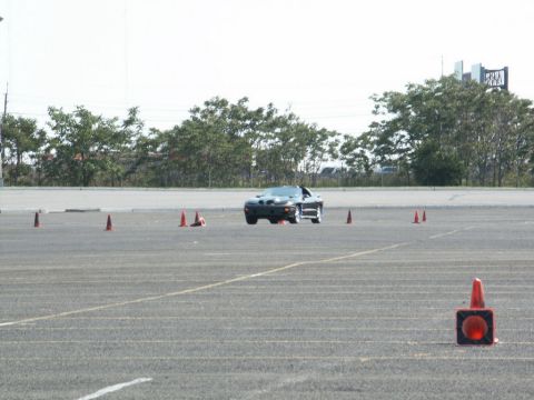 2001 Mercury Grand Marquis - A black sports car navigates a cone course on a bright, overcast day.