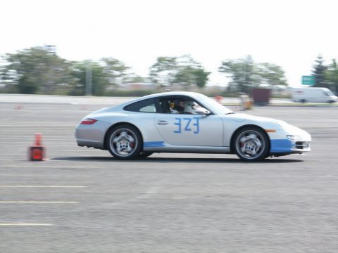 2001 Mercury Grand Marquis - A silver Porsche 911 with blue accents and the number 323 is seen on a race track, navigating around cones.