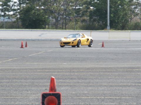 2001 Mercury Grand Marquis - A yellow sports car navigates a course marked by orange cones on a paved surface.