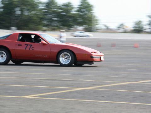 2001 Mercury Grand Marquis - A red sports car, marked with "77c", is seen in motion on a track, with another vehicle blurred in the background.