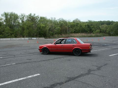 2001 Mercury Grand Marquis - Red sedan with racing numbers on the rear window is seen on an asphalt lot with orange cones.