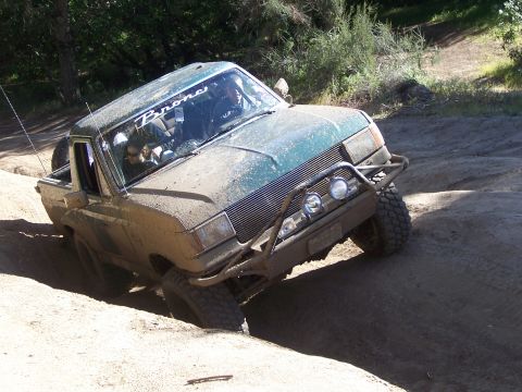1991 Ford Bronco - Mud-covered Ford Bronco navigates a challenging off-road terrain.