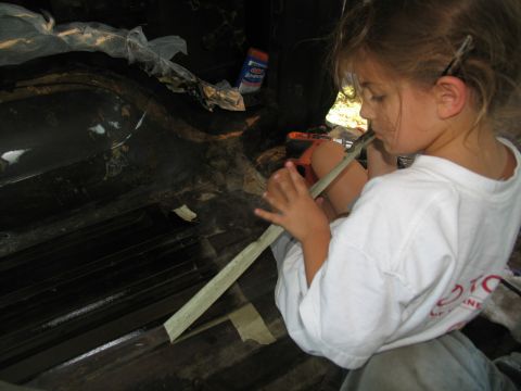 1978 Ford Bronco - A young girl is focused on a task inside a vehicle's interior, using tape.