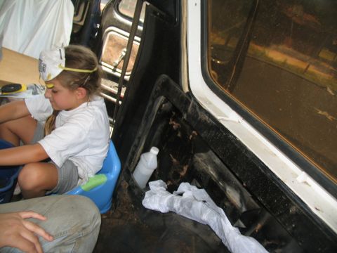 1978 Ford Bronco - A child sits in the interior of a vehicle, with a potty seat and cleaning supplies visible.
