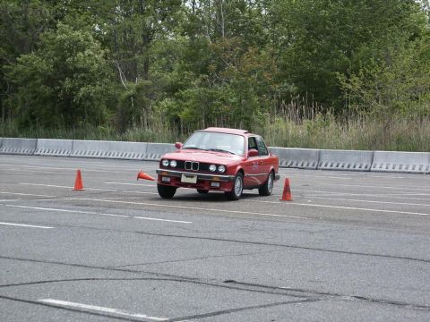 2001 Mercury Grand Marquis - A red BMW E30 coupe navigates an autocross course marked by orange cones.