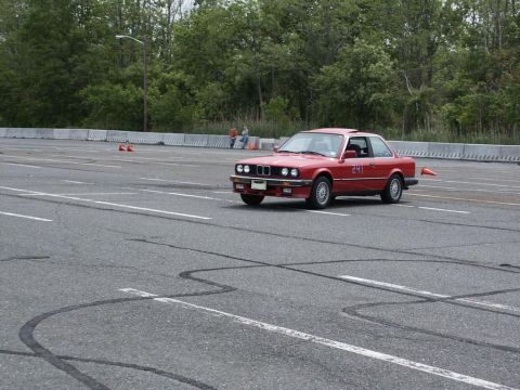 2001 Mercury Grand Marquis - A red BMW coupe with racing numbers on the door navigates a course marked by cones on a paved track.