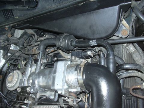 1996 Ford Crown Victoria - Close-up of a Ford engine's throttle body and intake piping, showing various hoses and electrical connectors.