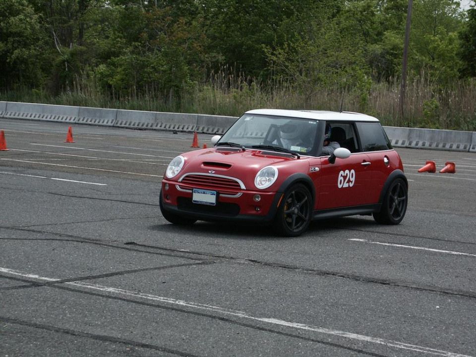 Red Mini Cooper S with number 629 on the door, driving on a track with orange cones
