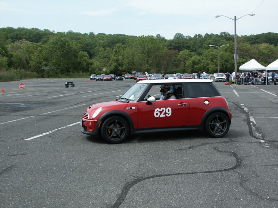 Red Mini Cooper with white roof and number 629 on its side, seen from the side at an autocross event