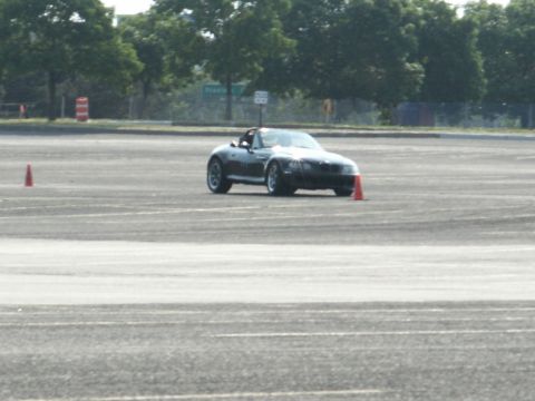 2001 Mercury Grand Marquis - A dark convertible sports car is seen on a paved surface, likely participating in an autocross event, with orange cones marking the course.