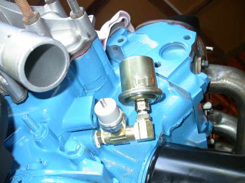 1990 Ford Bronco - A close-up view of engine components, including brass fittings and a silver sensor attached to a blue block.