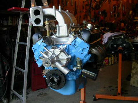 1990 Ford Bronco - Engine assembly with blue block and silver intake manifold, mounted on an orange engine stand.