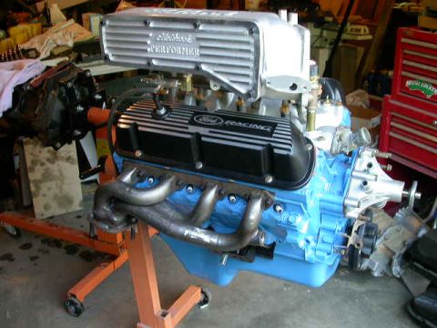1990 Ford Bronco - Ford V8 engine with aftermarket parts on an engine stand in a garage setting.