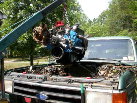 1990 Ford Bronco - Engine removal in progress on a green Ford truck, with the engine suspended by a crane.