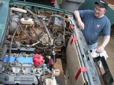 1990 Ford Bronco - A man works on the engine of a green vehicle, which has 'Ford Racing' visible on the valve cover.