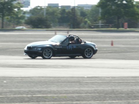 2001 Mercury Grand Marquis - A black convertible sports car with racing numbers is seen on a track during an event.