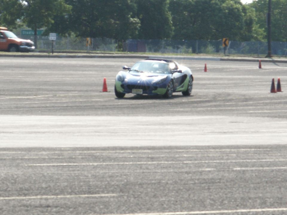 Blue and green sports car on asphalt course with orange cones