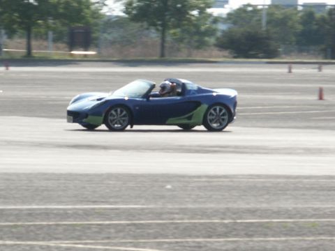 2001 Mercury Grand Marquis - A blue and green Lotus Elise convertible navigates a track with a driver wearing a helmet.