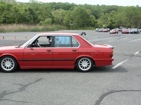 2001 Mercury Grand Marquis - A red sedan with racing numbers participates in an autocross event, with other vehicles in the background.