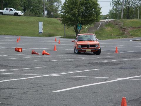 2001 Mercury Grand Marquis - Orange BMW 2002 navigates an autocross course marked by traffic cones.
