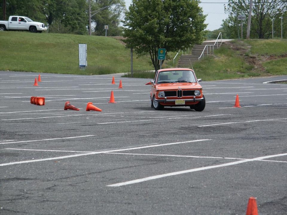 Orange BMW 2002 autocrossing with traffic cones on a paved lot