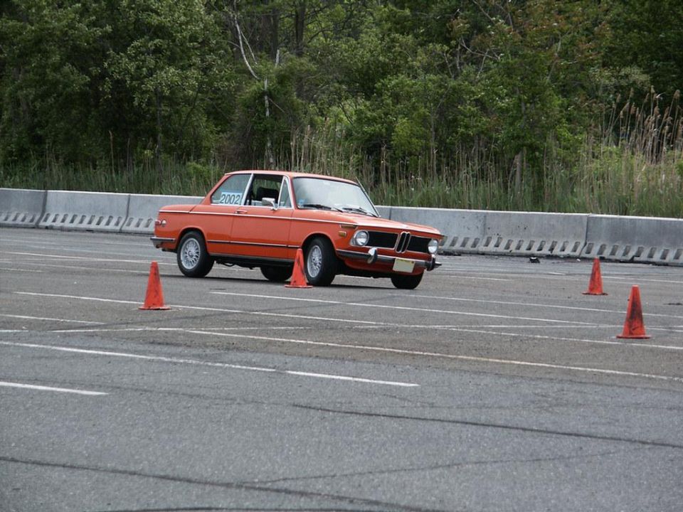 orange BMW 2002 driving on a track with cones