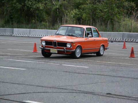 2001 Mercury Grand Marquis - An orange BMW 2002 is seen on a race track with orange cones.