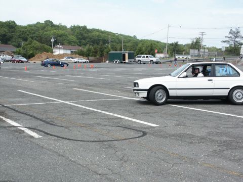 2001 Mercury Grand Marquis - A white BMW E30 coupe navigates an autocross course with cones marking the path.