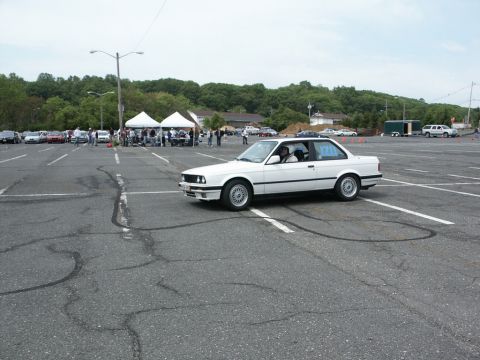 2001 Mercury Grand Marquis - A white coupe is driven in a parking lot during an event with tents and other cars in the background.
