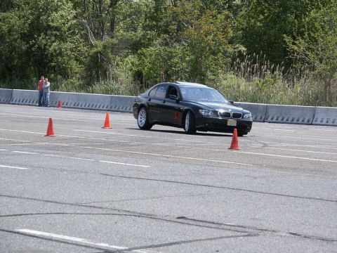 2001 Mercury Grand Marquis - A black BMW sedan maneuvers through an autocross event, marked by orange cones on the asphalt track.