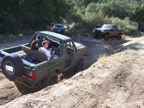 1991 Ford Bronco - Several vehicles navigate a dirt trail during an off-road event.