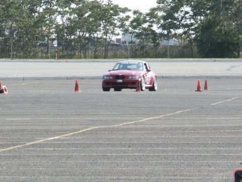 2001 Mercury Grand Marquis - A red sports car navigates a course marked by orange cones on a paved surface.