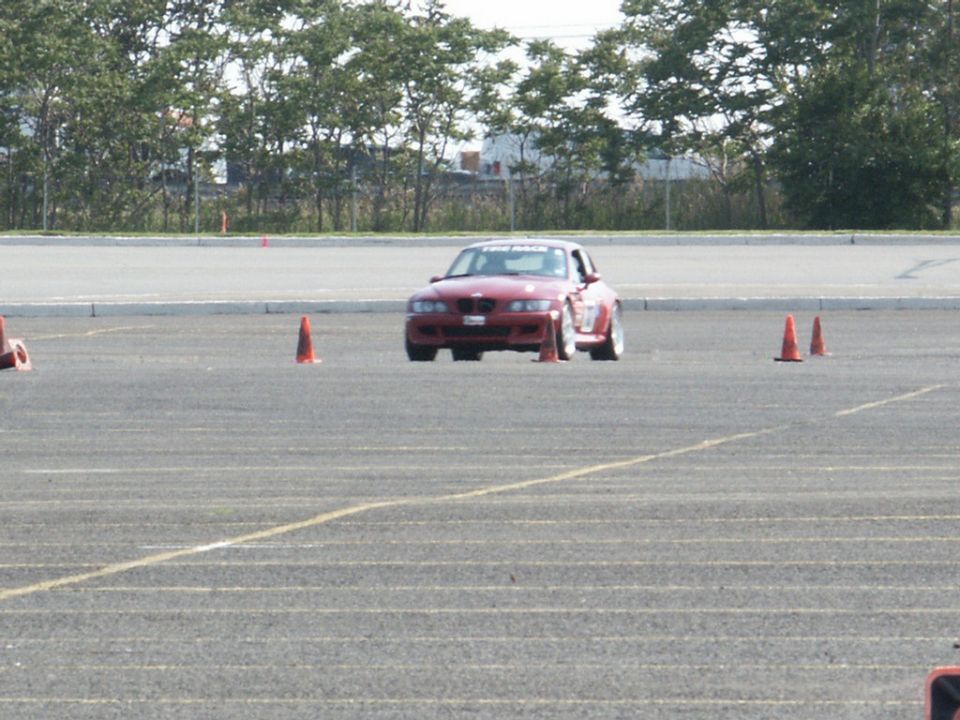 Red sports car on a paved track with orange cones, front view