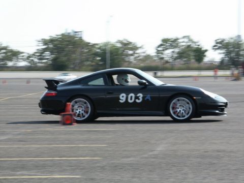 2001 Mercury Grand Marquis - A black Porsche 911 with racing number 903A navigates a course, with a driver in a helmet visible.