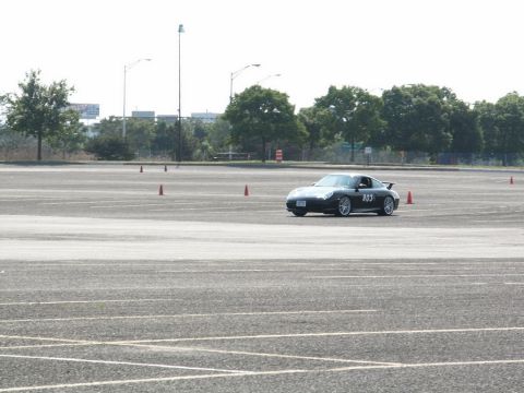 2001 Mercury Grand Marquis - A dark colored Porsche 911 is seen on a race track with orange cones marking the course.