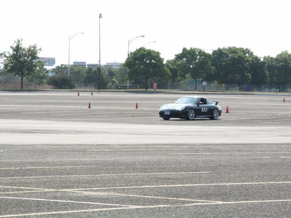 Porsche 911 with number 903 on the door driving on a track with orange cones
